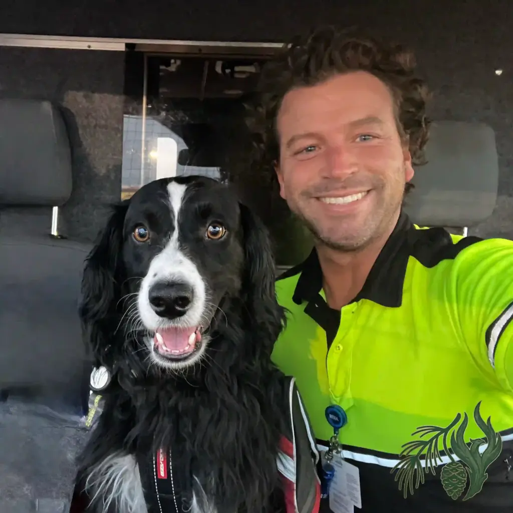 Kyle McCall, therapist, wearing a neon high-visibility shirt, smiling alongside his black and white service dog, Kauhlin, sitting in the cab of an ambulance while working in Amarillo, Texas.
